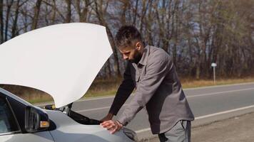 une homme réparations le voiture dans le milieu de le Autoroute. transport, en voyageant concept video