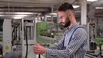 Smiling industrial specialist standing in a metal construction manufacture. Smart factory worker using machine in factory workshop. Industry and engineering concept video