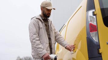 A turkish man unplugs charging cable electric vehicle. Male hand disconnects power connector into cargo EV car video