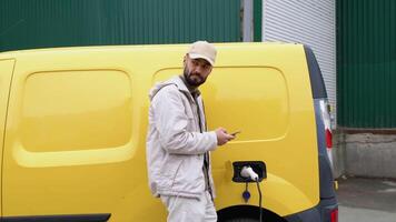 Deliveryman charging cargo electric car near warehouse. Green energy, eco friendly fuel video