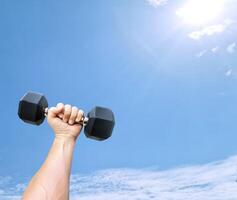 Man holding a dumbbell in his hand There is a sky in the background. photo