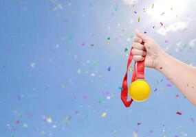 Holding a gold medal celebrating success sky background photo