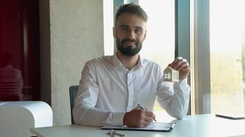 Spaans mannetje makelaar Holding wit huis model- tekens een contract voor de uitverkoop van een appartement video