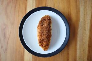 un plato de triturado pollo un pan en el mesa foto
