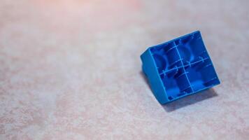 Blue plastic building block on the floor. One Rear toy. photo