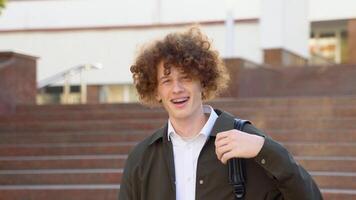 Happy handsome successful student with braces, standing on the steps and smiling, looks into the frame outdoors on the street near the university video