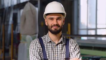 Young man in protective helmet working in factory. Portrait of worker in factory video