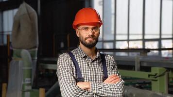 Young man in protective helmet working in factory. Portrait of worker in factory video