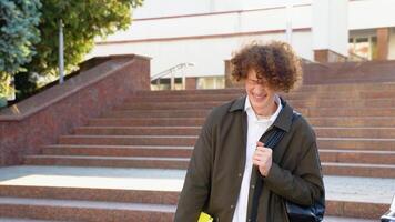 Happy handsome successful student with braces, standing on the steps and smiling, looks into the frame outdoors on the street near the university video