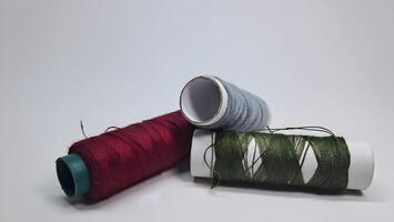 three spools of thread on a white surface photo