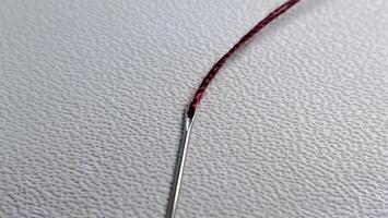 a needle with red thread on a white surface photo