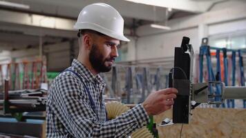 Professional heavy industry engineer worker wearing safety uniform and hard hat uses computer. Smiling industrial specialist standing in a metal construction manufacture video