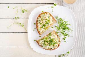 Delicious toast with pate boiled egg, cucumber and cream cheese on a white plate. Healthy eating, breakfast. Keto diet food. Tasty food. Top view photo