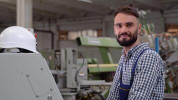 profesional pesado industria ingeniero trabajador vistiendo la seguridad uniforme usos computadora. sonriente industrial especialista en pie en un metal construcción fabricar video