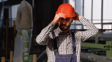 ritratto di il Manuale uomo lavoratore nel uniforme e protettivo bicchieri mette su un' casco e guardare per il telecamera video