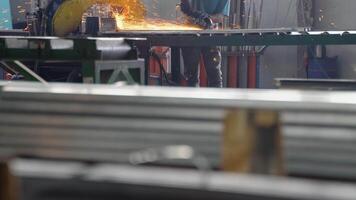 de interieur van een zwaar bouwkunde fabriek met een industrieel arbeider gebruik makend van een hoekig slijpen machine en een snijdend metaal pijp video