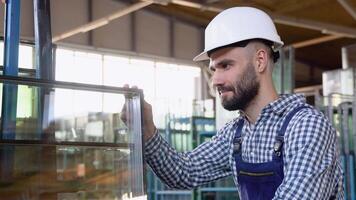 Professional man worker in uniform and helmet in a window warehouse prepares windows for sending video