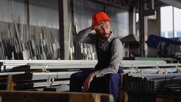 Tired worker in a helmet at a large metalworking plant. Shiftman in the finished product warehouse video