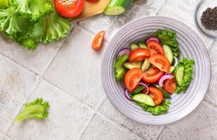 Healthy fitness fresh simple salad. Close up photo of healthy food Vegetable green salad cucumbers tomatoes onions flat lay top view copy space