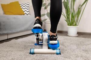 Home fitness, woman doing exercises on a stepper at home close up photo