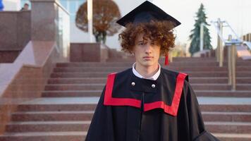 un joven gracioso graduado en el maestría manto corrige el sombrero en su cabeza video