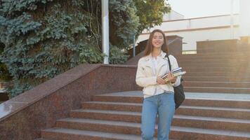 giovane ragazza alunno a piedi giù il le scale vicino Università o ufficio costruzione. hold libri. all'aperto video