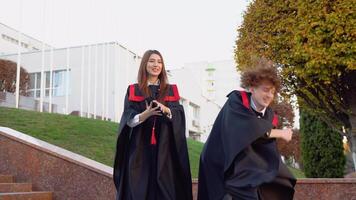 el chico y niña graduados de el maestría la licenciatura son fácil y alegremente lanzamiento su maestría sombreros arriba video