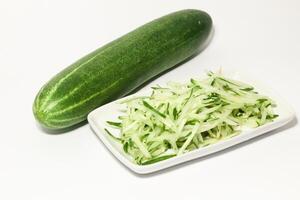 Grated cucumber in a bowl on white background. Healthy vegetarian ingredients photo