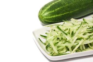 Grated cucumber in a bowl on white background. Healthy vegetarian ingredients photo