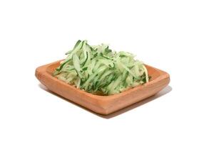 Grated cucumber in a bowl on white background. Healthy vegetarian ingredients photo