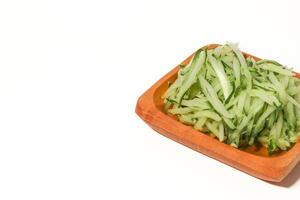 Grated cucumber in a bowl on white background. Healthy vegetarian ingredients photo