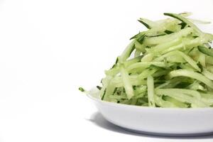 Grated cucumber in a bowl on white background. Healthy vegetarian ingredients photo