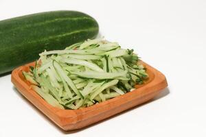 Grated cucumber in a bowl on white background. Healthy vegetarian ingredients photo