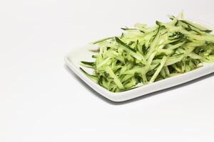 Grated cucumber in a bowl on white background. Healthy vegetarian ingredients photo