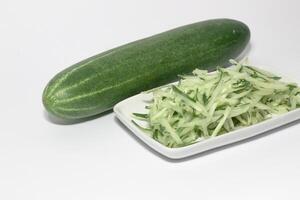 Grated cucumber in a bowl on white background. Healthy vegetarian ingredients photo