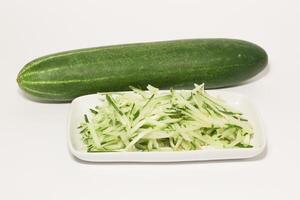 Grated cucumber in a bowl on white background. Healthy vegetarian ingredients photo