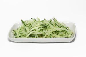 Grated cucumber in a bowl on white background. Healthy vegetarian ingredients photo