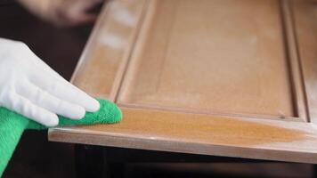 Remonier worker in a gloves degreases the surface before painting a wooden product, kitchen facade close up video