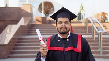 gelukkig afstuderen. gelukkig Indisch Mens in diploma uitreiking jurken houdt een diploma video