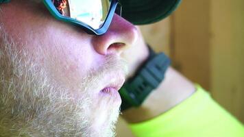 homme en mangeant la glace crème. fermer portrait de Jeune branché homme dans lunettes de soleil en mangeant la glace crème dans été chaud temps sur le plage, avoir amusement et bien ambiance. video