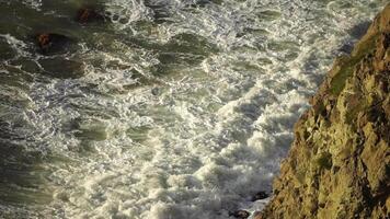 Sturm Welle Sonnenuntergang. Sturm Welle Annäherung das Küste beim golden Verbrennung Sonnenuntergang mit sprühen entstanden durch Wind im Hintergrundbeleuchtung. Seelandschaft mit groß brechen Wellen. Wetter und Klima Veränderung video