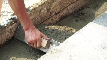 Construction, Worker Hands smooth wet cement in wooden frame at a construction site during daytime to ensure an even surface video