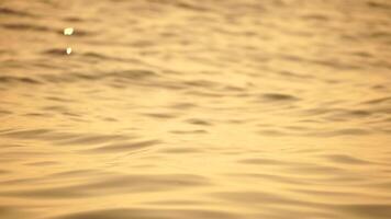 verschwommen golden Meer beim Sonnenuntergang. das Sonne spiegelt und funkelt auf das Wellen mit Bokeh, leuchten das golden Meer. Urlaub Erholung Konzept. abstrakt nautisch Sommer- Ozean Sonnenuntergang Natur Hintergrund. video