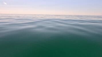 mare acqua superficie. Basso angolo Visualizza al di sopra di chiaro azzurro mare acqua. sole bagliore. astratto nautico estate oceano natura. vacanza, vacanza e viaggio concetto. nessuno. lento movimento. tempo metereologico e clima modificare video