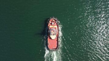 tug boat in open calm sea, helps large container ships maneuver. Aerial top down view, maritime industry, oceanic transportation or business concepts. video