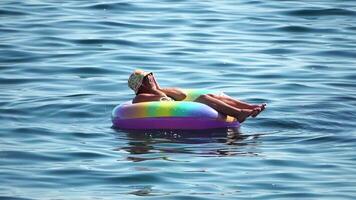 verano vacaciones mujer flotadores en un inflable rosquilla colchón, un agua juguete nadar anillo. irreconocible joven mujer relajante y disfrutando familia verano viaje Días festivos vacaciones en el mar. lento movimiento video