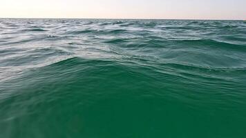 Sea water surface. Low angle view from kayak, camera flies over the clear green sea water. Nobody. Holiday recreation concept. Abstract nautical summer ocean nature. Slow motion. Close up video