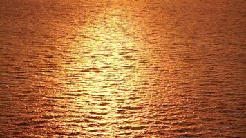 Sea water surface. Aerial view on golden sea water at sunset. Sun glare. Abstract nautical summer ocean nature. Holiday, vacation and travel concept. Nobody. Slow motion. Weather and climate change video