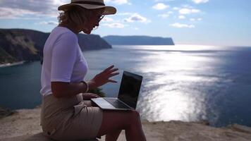 Digital Nomade, Geschäft Frau Arbeiten auf Laptop durch das Meer. ziemlich Dame Tippen auf Computer durch das Meer beim Sonnenuntergang, macht ein Geschäft Transaktion online von ein Distanz. freiberuflich, Fernbedienung Arbeit auf Ferien video