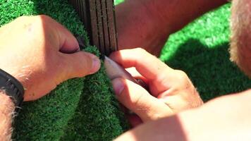 Man Cuting Artificial Grass carpet with knife. Artificial turf. Close up on hands. video